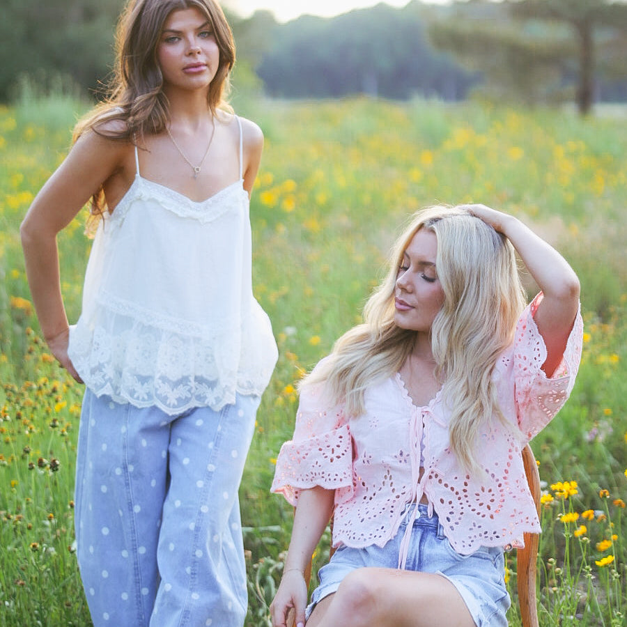 Two women in a field of wildflowers with trees in the background